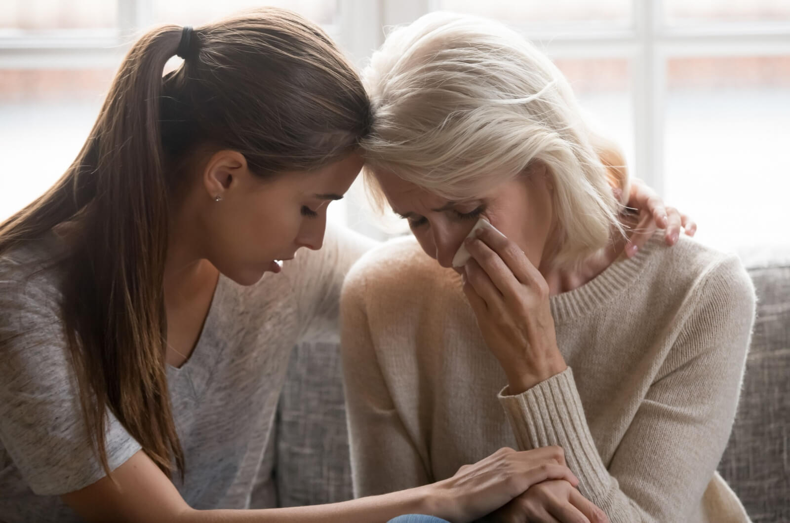 An adult child providing emotional support to a distraught parent by holding them.
